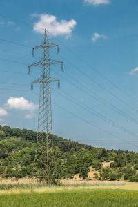 Low angle view of electricity pylon on field against sky