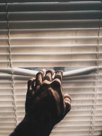 Cropped hand opening blinds at home