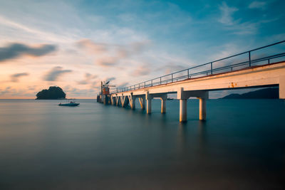 Bridge over sea against sky at sunset