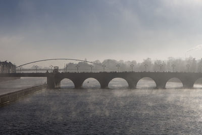 Arch bridge over river against sky