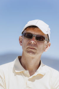 Man wearing sunglasses and cap against clear sky