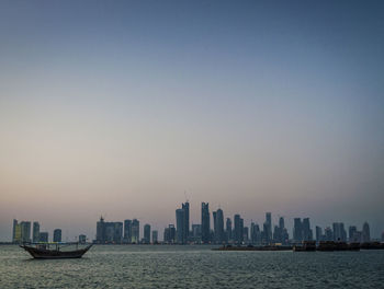 Sea by modern buildings against clear sky