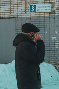 Man standing against snow covered wall