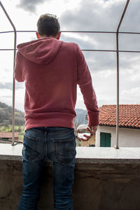 Rear view of man standing by window