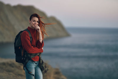 Young woman standing in sea against sky