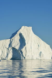 View of majestic iceberg in sea against sky