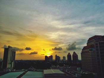 Cityscape against cloudy sky at sunset