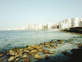 Scenic view of sea by city against clear sky