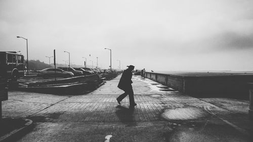 Silhouette man walking on footpath against sky