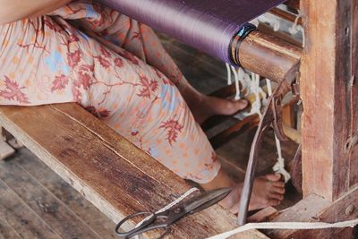 Low section of woman weaving loom in workshop