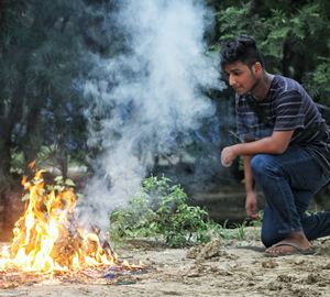 Young man sitting on tree