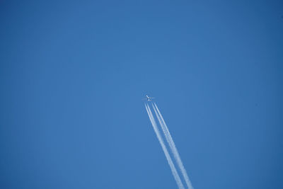 Low angle view of vapor trail against blue sky