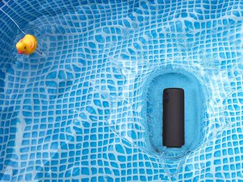 Rubber duck and speaker floating in swimming pool