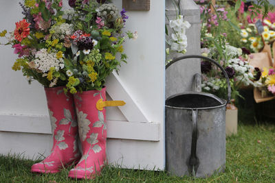 Plants growing rubber boots by watering can in garden