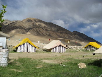 Tents at desert against cloudy sky