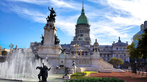 Statue in city against cloudy sky