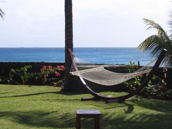 Hammock at park by sea against sky