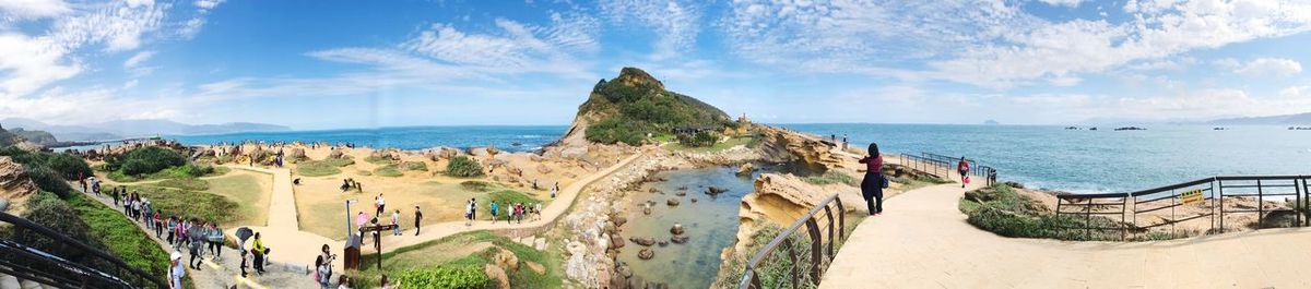 Panoramic view of people at beach against sky