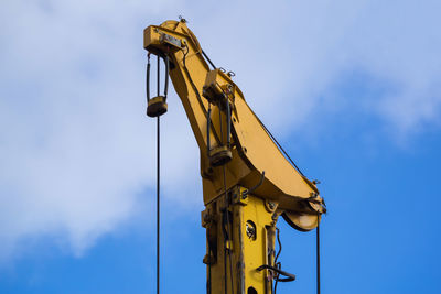 Low angle view of construction machinery against cloudy sky