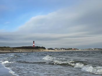 Lighthouse by sea against sky