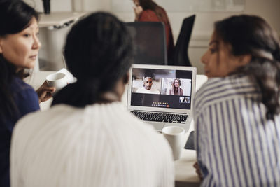 Businesswomen doing video call with colleagues through laptop at coworking office