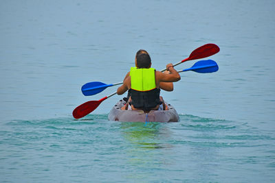 Rear view of men kayaking in sea