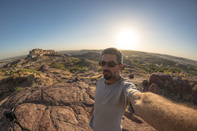 Portrait of man standing on mountain against clear sky