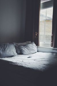 Close-up of laptop on bed by window at home