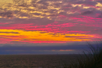 Scenic view of sea against dramatic sky during sunset