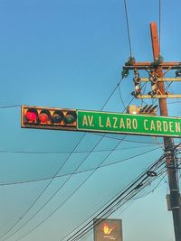 Low angle view of information sign against clear blue sky
