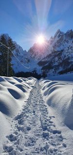 Scenic view of snow covered mountains against bright sun