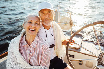 Portrait of smiling couple sitting on sailboat in sea