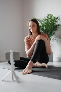 Portrait of young woman sitting on floor at home