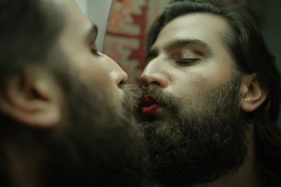 Man wearing lipstick while kissing against mirror