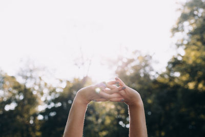 Hands raised and intertwined against horizon of trees 