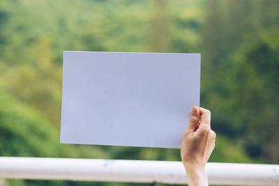 Midsection of person holding paper against white background