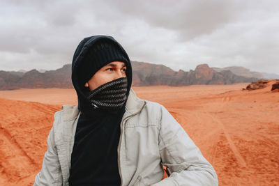 Portrait of mid adult man standing in desert against sky