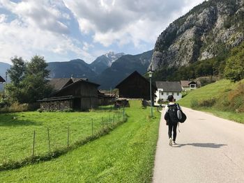 Rear view of man walking on road against sky