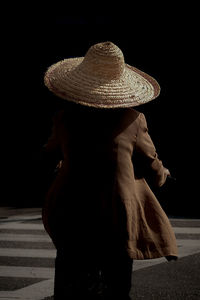 Rear view of woman hat against black background