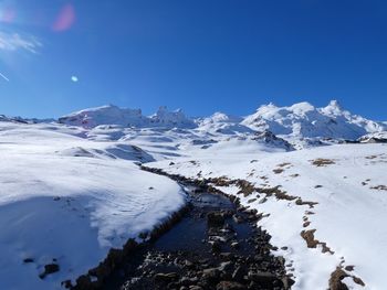 Scenic view of snowcapped mountains against clear blue sky