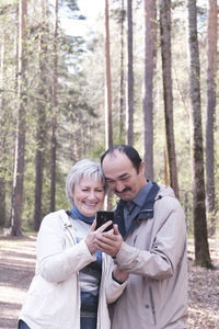 Happy friends standing by tree in forest