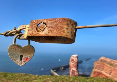 Close-up of rusty padlock hanging on metal against sky