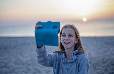 Portrait of smiling woman on beach during sunset