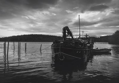 Boats in lake against cloudy sky