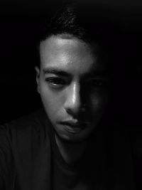 Close-up portrait of young man against black background