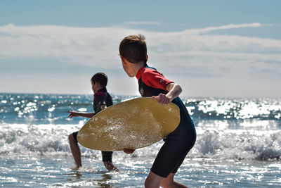 Rear view of boys on beach against sea