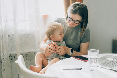 Happy woman using phone while sitting on laptop