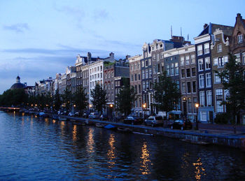 Buildings by river against sky in city