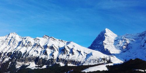 Scenic view of snowcapped mountains against blue sky