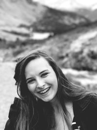 Portrait of cheerful young woman standing against mountain